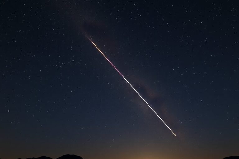 Meteoro cruzando un cielo estrellado sobre cerros del desierto