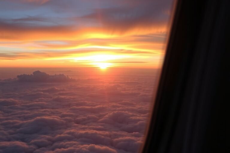 Vista del atardecer sobre las nubes desde la ventana de un avión